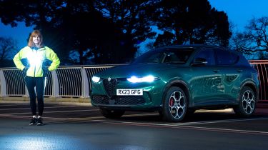 Auto Express pictures editor Dawn Grant standing next to the Alfa Romeo Tonale PHEV at night